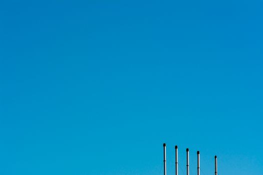 Minimalist image of industrial poles under a clear blue sky, highlighting clean energy.