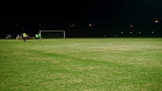 晚上，我看到一个足球场，球员和球门柱在泛光灯下