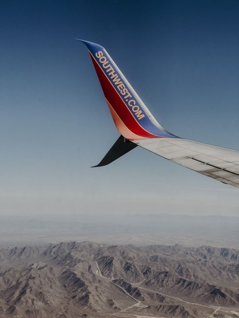 Photo by James Davis Airplane wing of Southwest Airlines seen over rugged desert mountains.