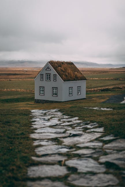 A picturesque house in a rural setting with a cobblestone path leading to it under cloudy skies.