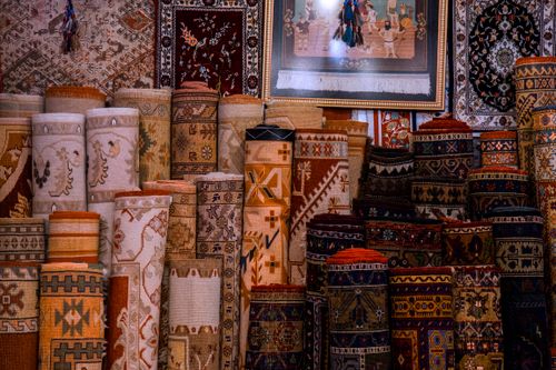 Free Vibrant collection of traditional rolled carpets on display in a cultural bazaar setting. Stock Photo