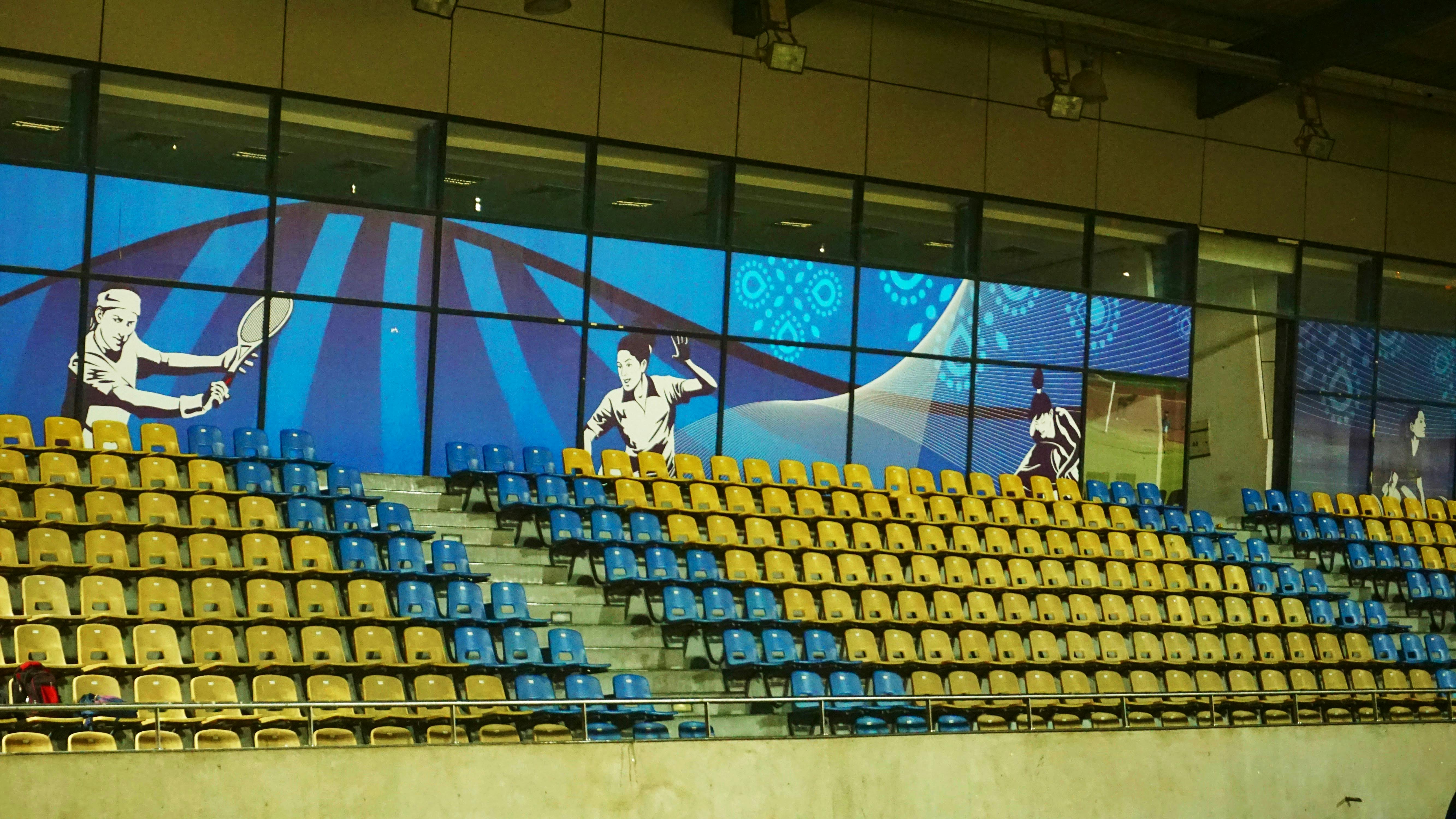 这座充满活力的现代体育场内部，配有蓝色和黄色座椅以及体育主题壁画