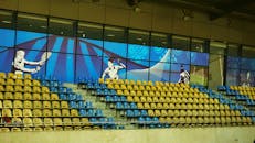 这座充满活力的现代体育场内部，配有蓝色和黄色座椅以及体育主题壁画