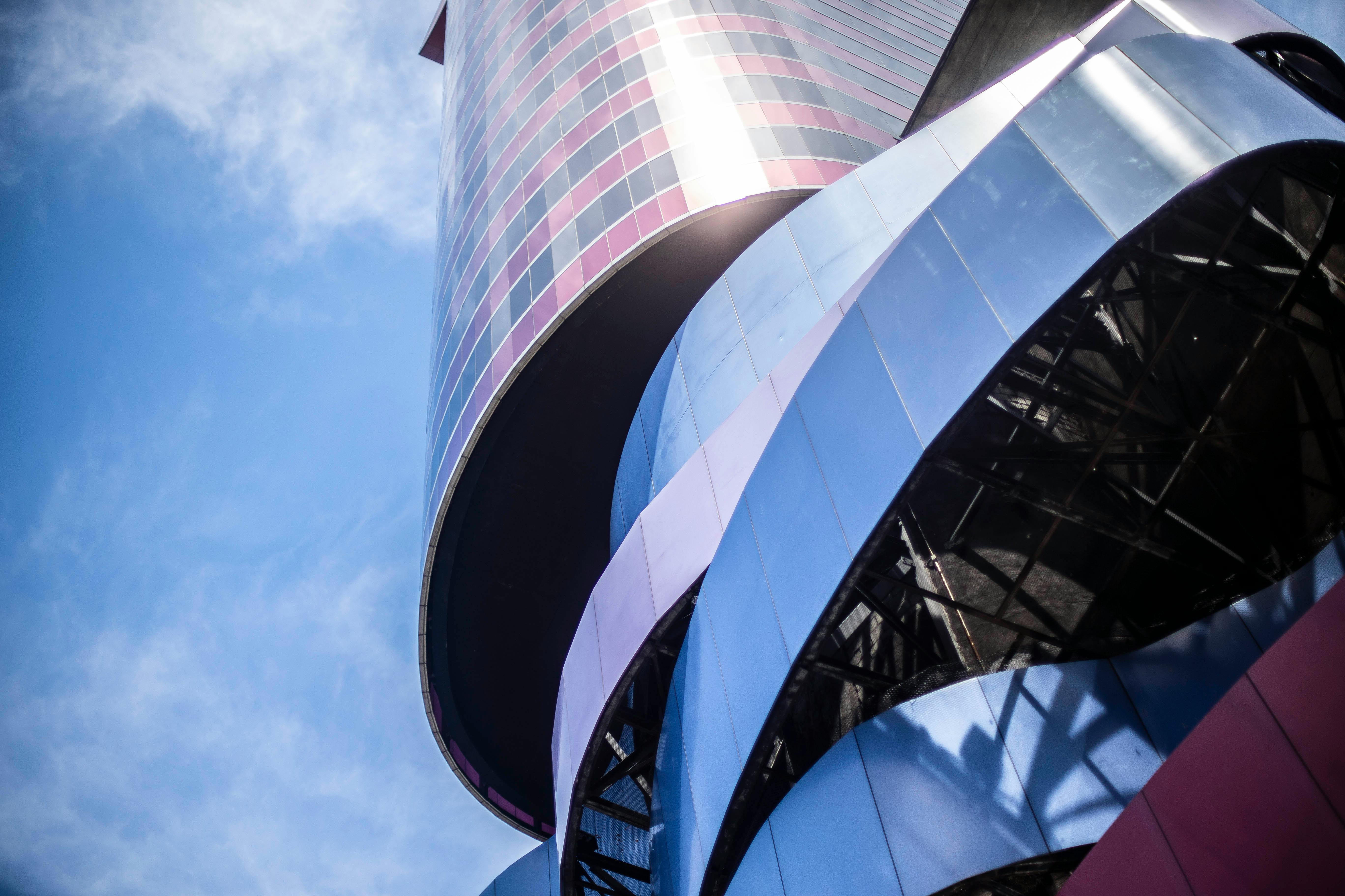 从低角度仰望，现代摩天大楼那充满活力的弧形立面，映衬着清澈的蓝天