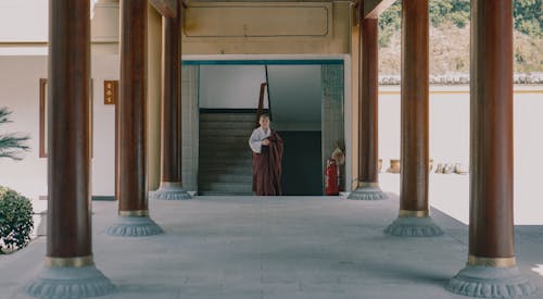 Free Buddhist Monk Standing in Temple Entrance Stock Photo