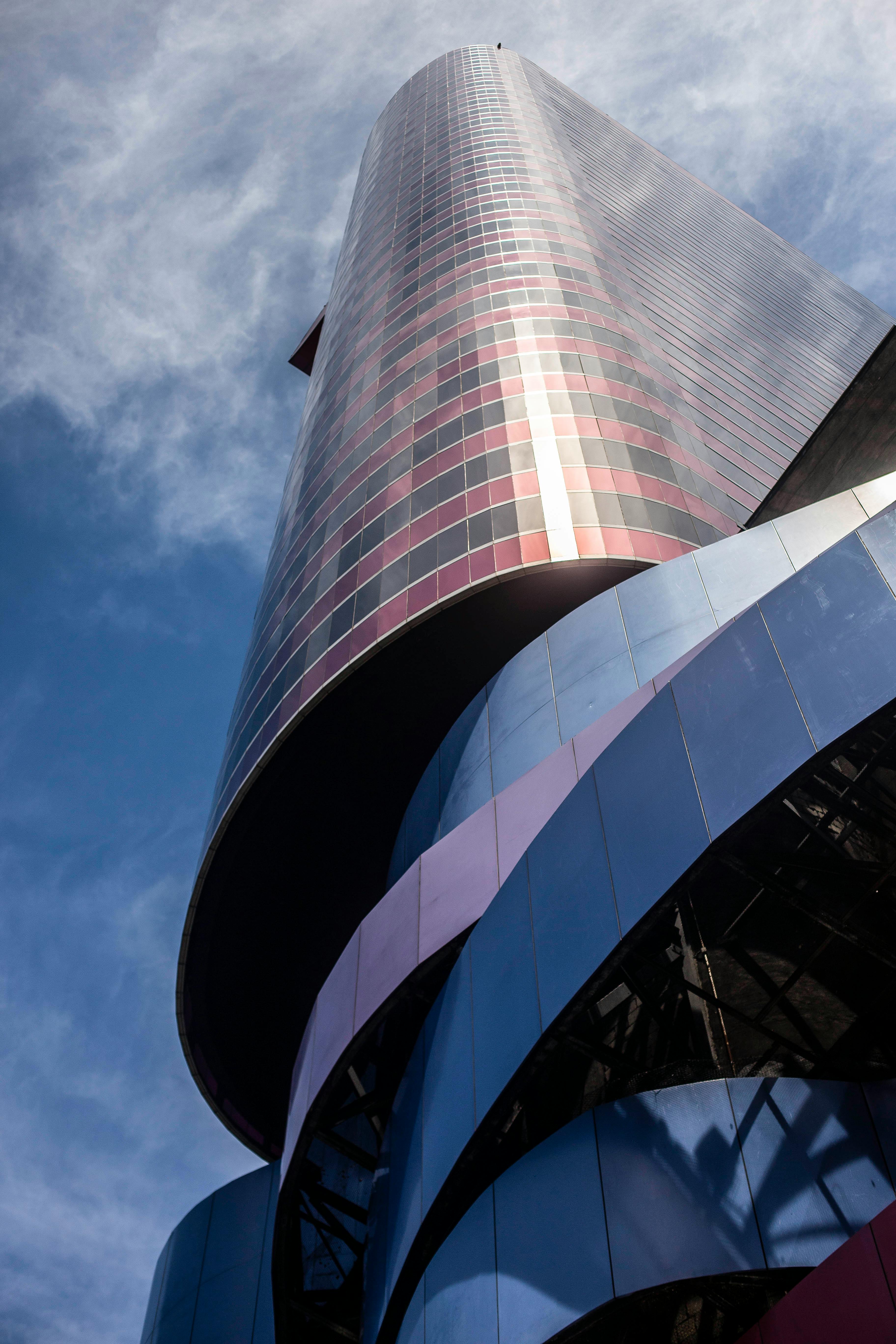 低角度镜头下的现代摩天大楼，弧形玻璃立面映衬着蓝天