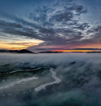 Stunning aerial capture of Tell, WI at dusk with river and fog illuminated by a colorful sunset.