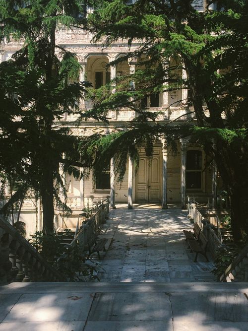 Free Elegant historic mansion in Istanbul with lush greenery and classic architecture casting intricate shadows. Stock Photo