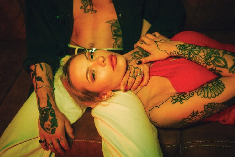 Tattooed Woman Lying On Man Lap