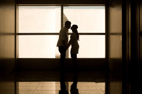 Hombre Y Mujer Tomados De La Mano Cerca De La Ventana De Cristal