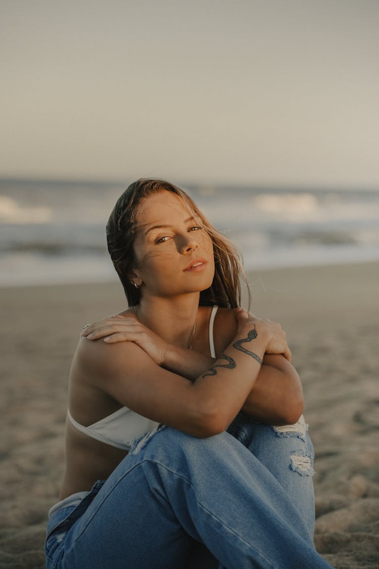 Model Sitting And Posing With Arms Crossed On Beach