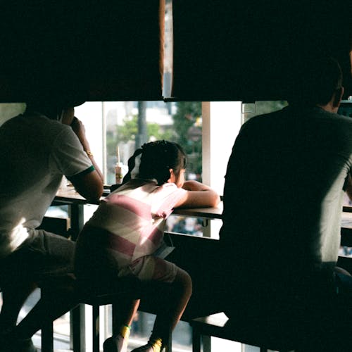 Back View of People Sitting by the Table near the Window in a Cafe