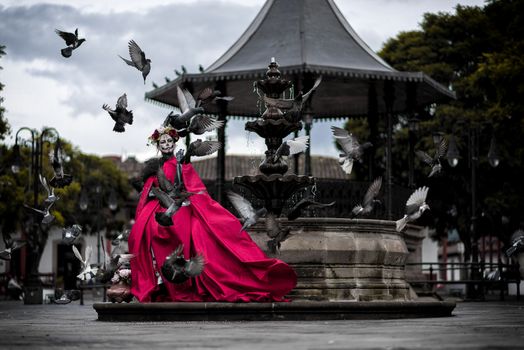 Woman Dressed for Mexican Death Festival Standing next to a Fountain 