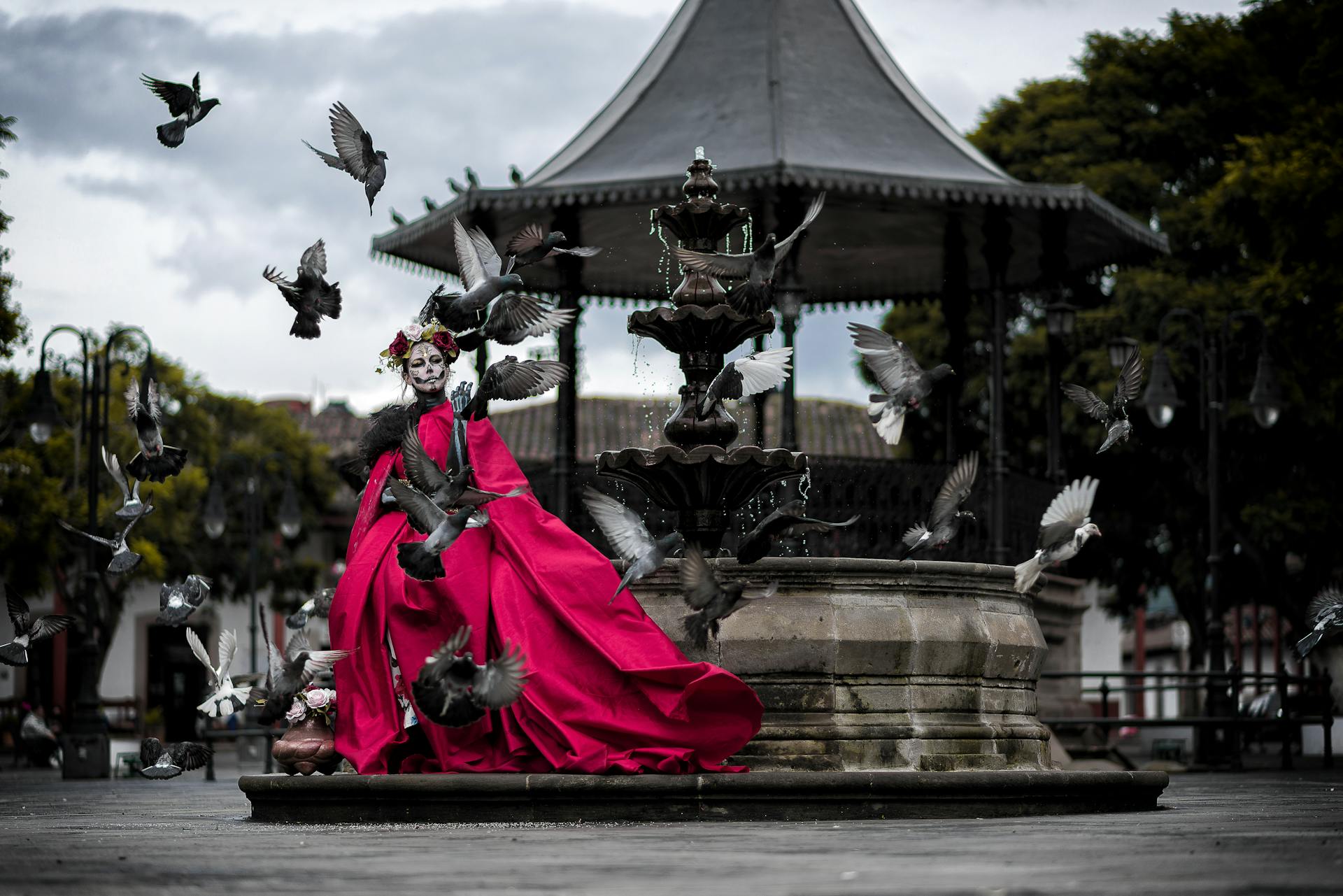 Woman Dressed for Mexican Death Festival Standing next to a Fountain