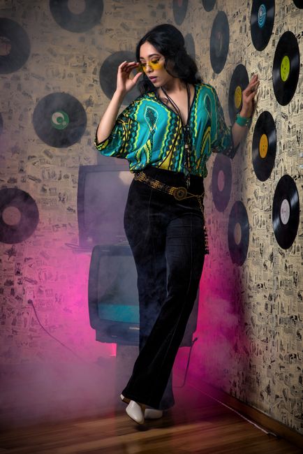 Fotomural Mujer con atuendo de los años 70, discos de vinilo y ambiente ahumado, elegante y vibrante.