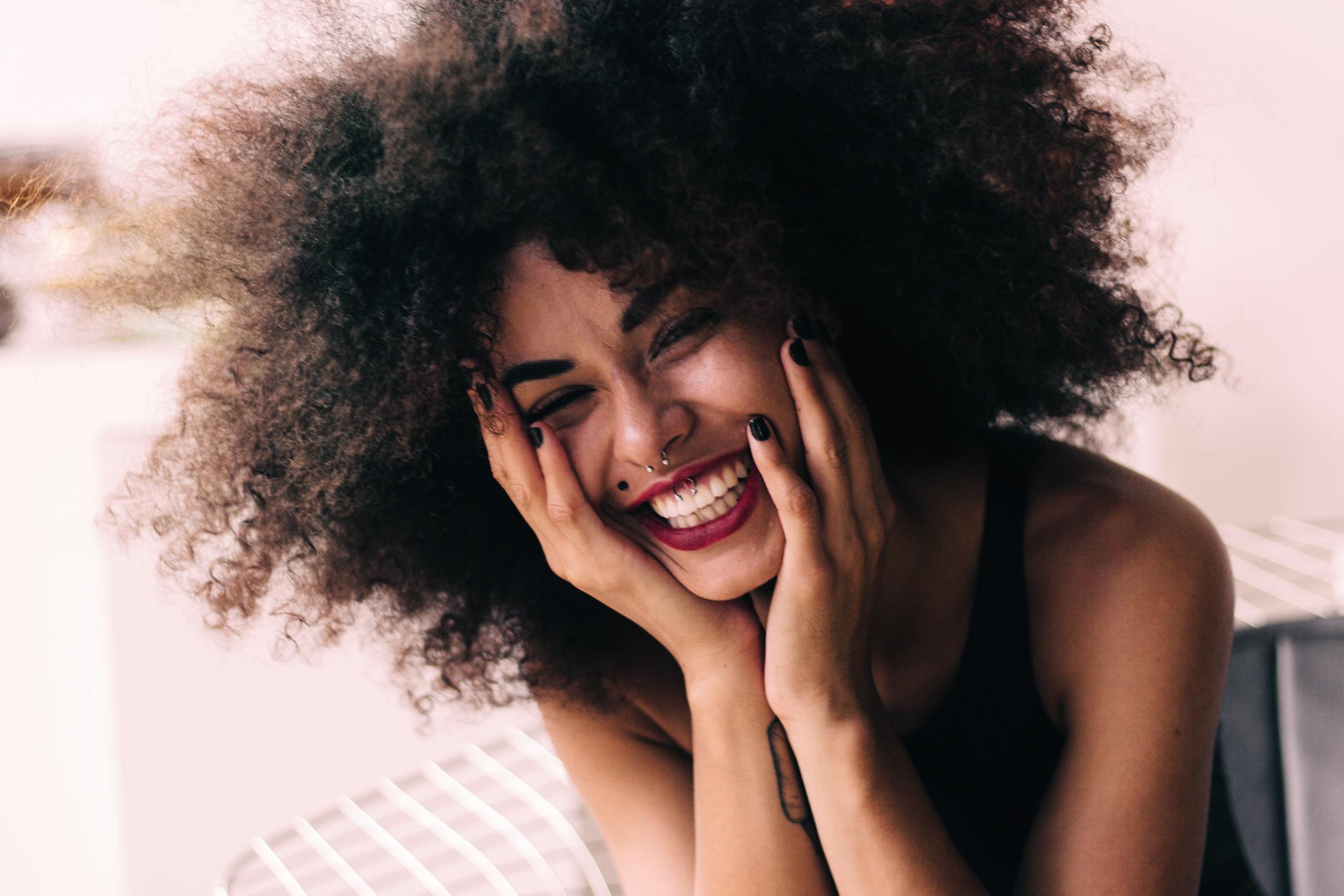 Photo of Smiling Woman with Hands on Her Face