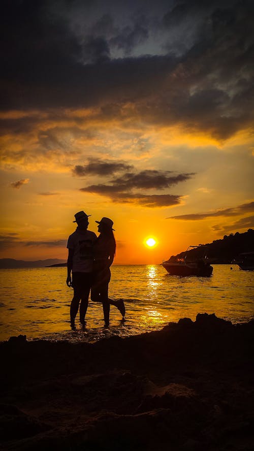 Silhouette of a Couple Standing on the Shore in the Evening 