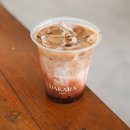 Free Chilled iced coffee in a Dakara Kopi cup on a wooden table in Yogyakarta. Stock Photo
