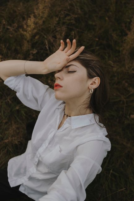 Stylish woman posing outdoors in Berlin, wearing a white shirt and red lipstick.