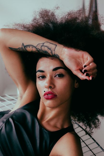 Striking portrait of a tattooed woman with curly hair posing confidently in São Paulo, Brazil.