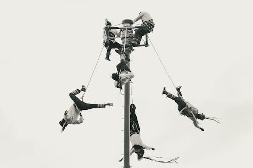 Men Hanging on Pole at Festival