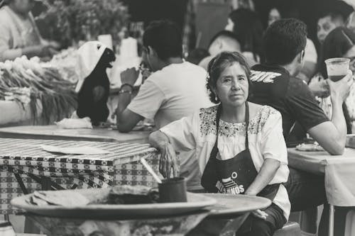Woman in Apron Sitting among People at Restaurant