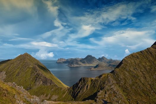 Breathtaking landscape of rocky mountains and ocean in a serene setting under a vibrant blue sky.