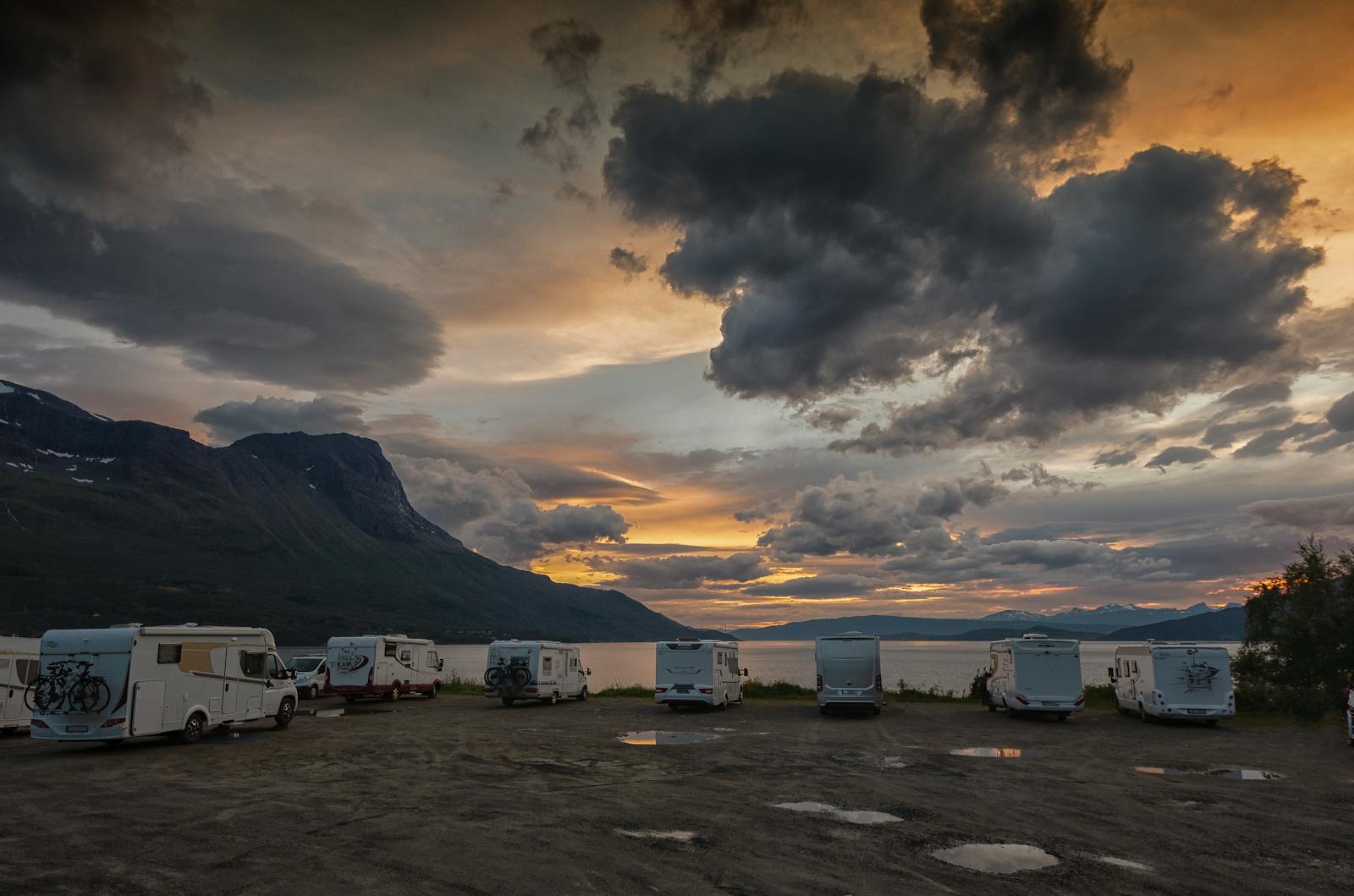 Flere bobiler parkert ved fjorden på Langstranda nær Narvik i kveldlys.