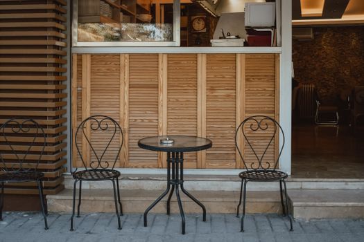 Charming outdoor cafe scene with vintage chairs and a table, perfect for relaxing in a city environment.