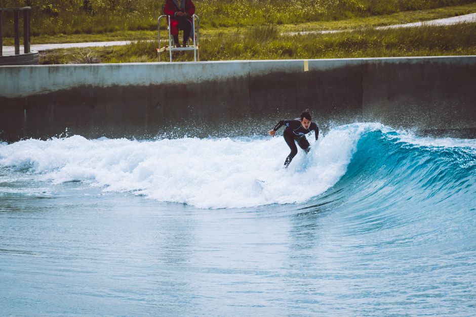 Surfer riding a wave at Bristol's indoor surf camp. Perfect for sport and adventure enthusiasts.