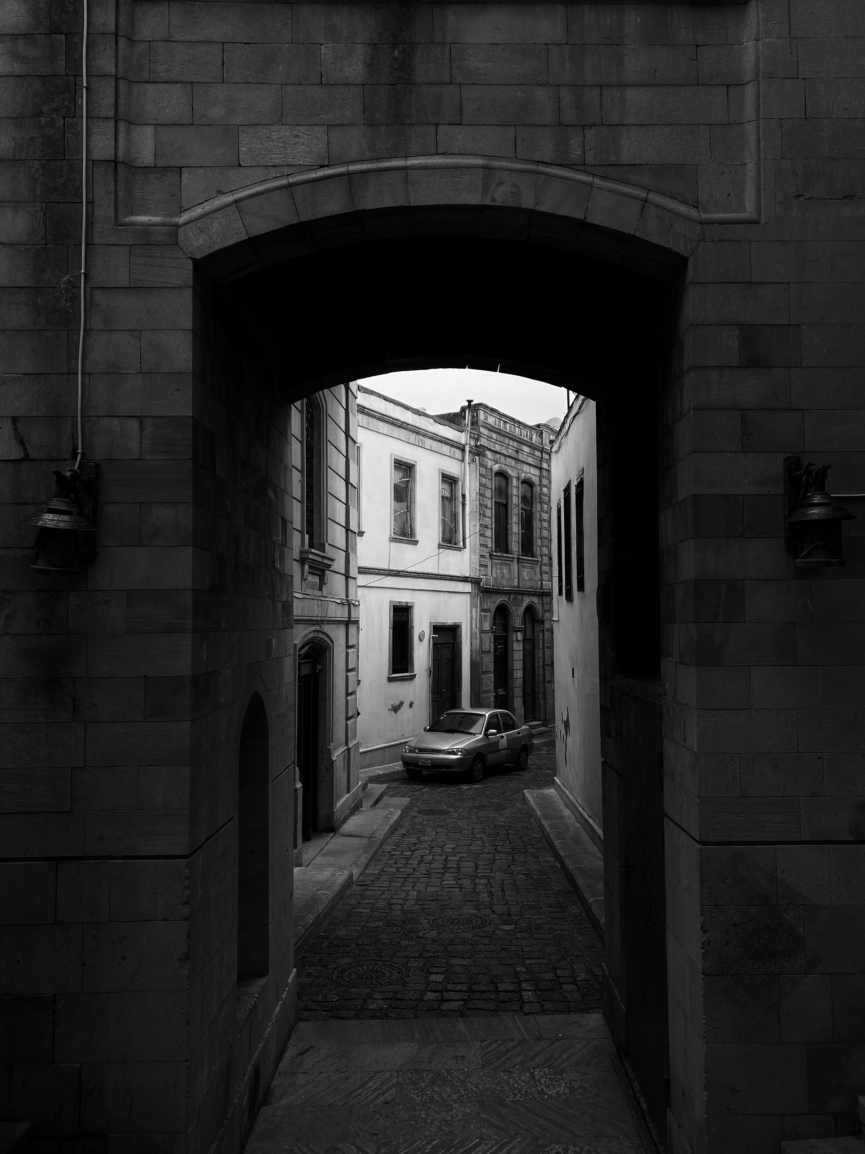 Black and white photo of a quaint alley with arches and cobblestone in Baku, Azerbaijan.
