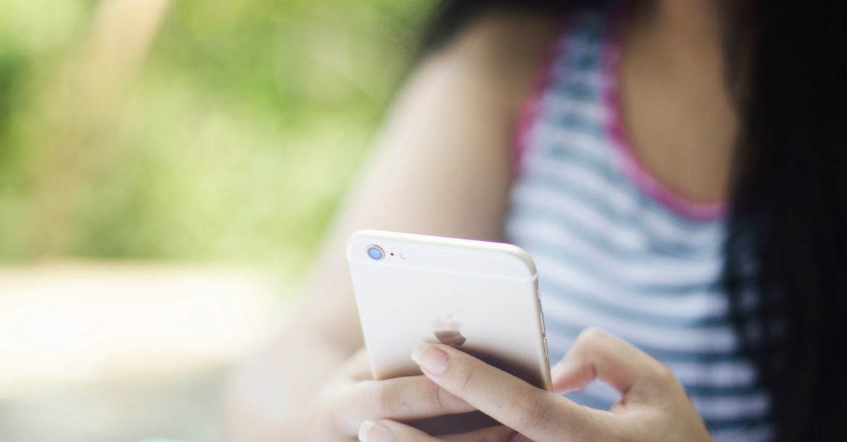 Uma mulher usando um smartphone ao ar livre em um ambiente relaxante.