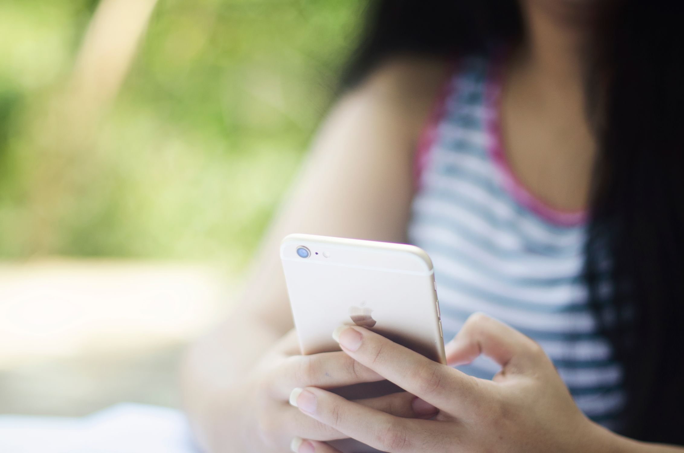 Mulher jovem ao ar livre utilizando smartphone para prática de bem-estar e equilíbrio digital