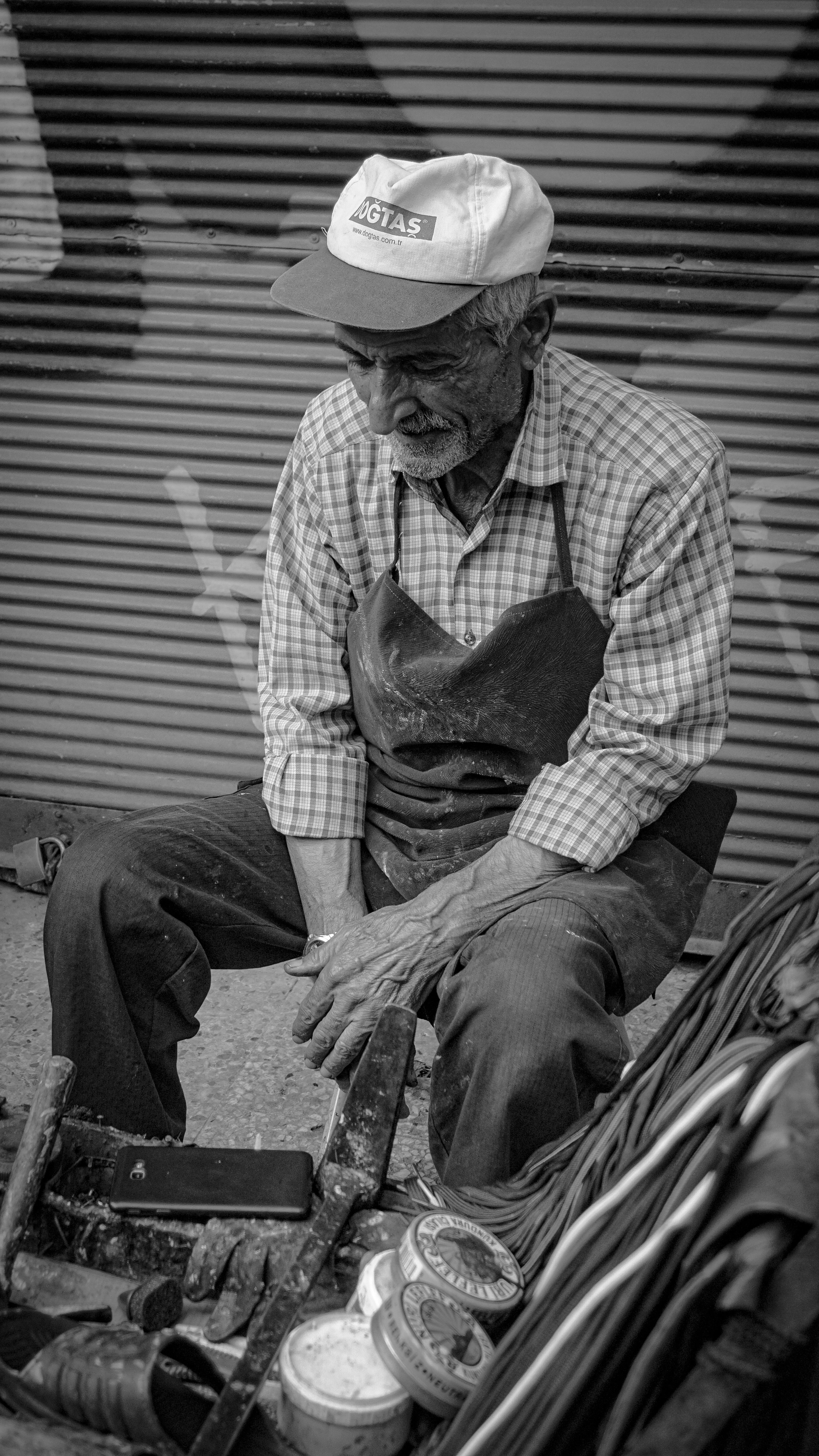 Captivating black and white portrait of an elderly man sitting on city streets, capturing urban life.