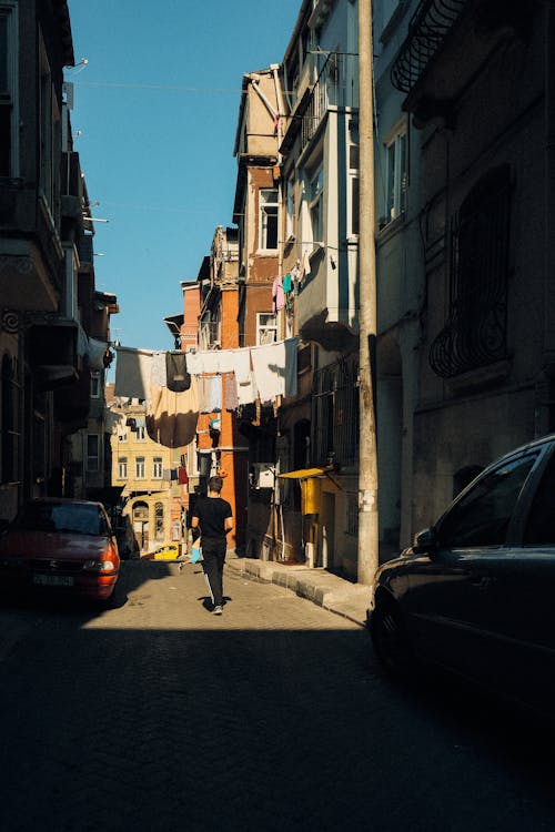 Back of a Man Walking under Laundry Drying over an Alley