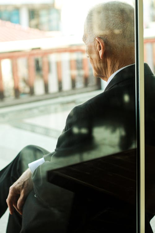 Elderly Man Sitting behind Window
