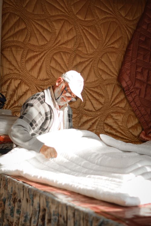 Free Senior tailor expertly crafting quilts, showcasing traditional skills. Stock Photo