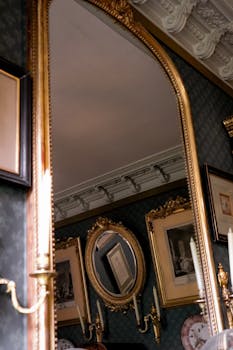 Luxurious Parisian room with ornate mirror and classic artwork, showcasing rich interior design.