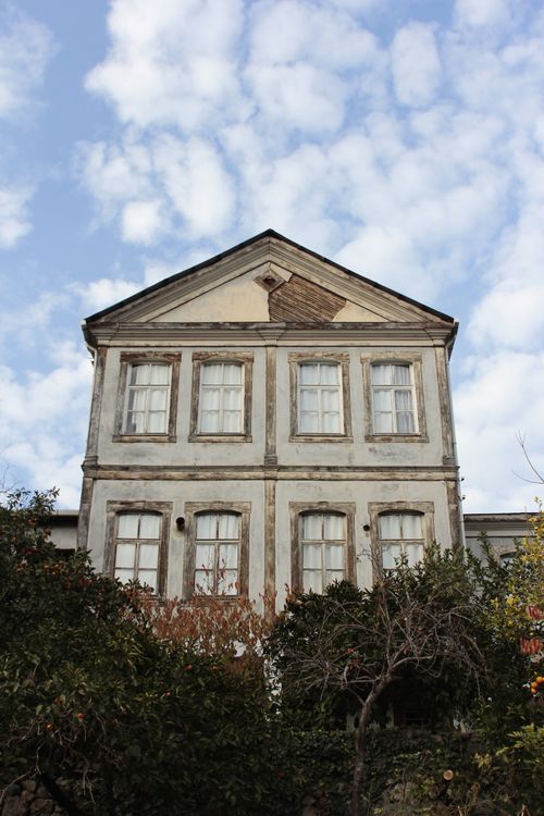 Free Old building facade with trees and cloudy sky, showcasing timeless architecture. Stock Photo