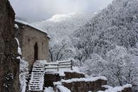 A scenic snowy landscape featuring a stone structure and evergreen forest.
