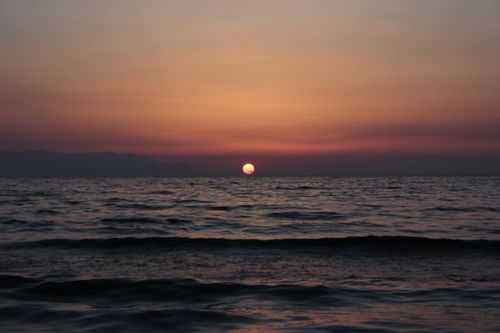 Free Serene sunset over the ocean with warm hues reflecting on wavy water, creating a calm atmosphere. Stock Photo