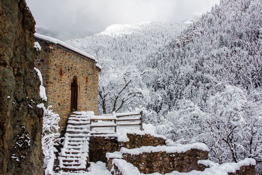 A stone house amidst a snowy forest, showcasing winter's serene beauty.