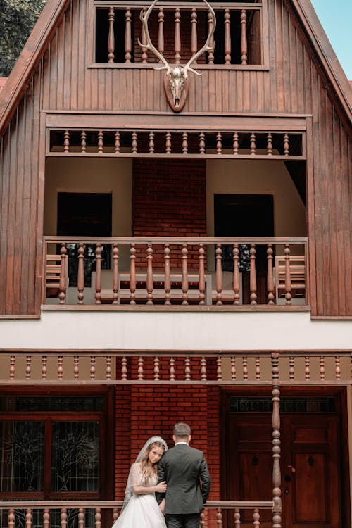 Newlyweds Standing by Wooden House