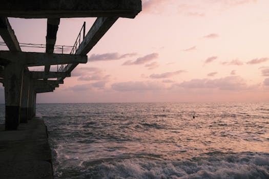 A tranquil view of a pier extending into the ocean under a serene sunset sky, perfect for travel or relaxation themes.