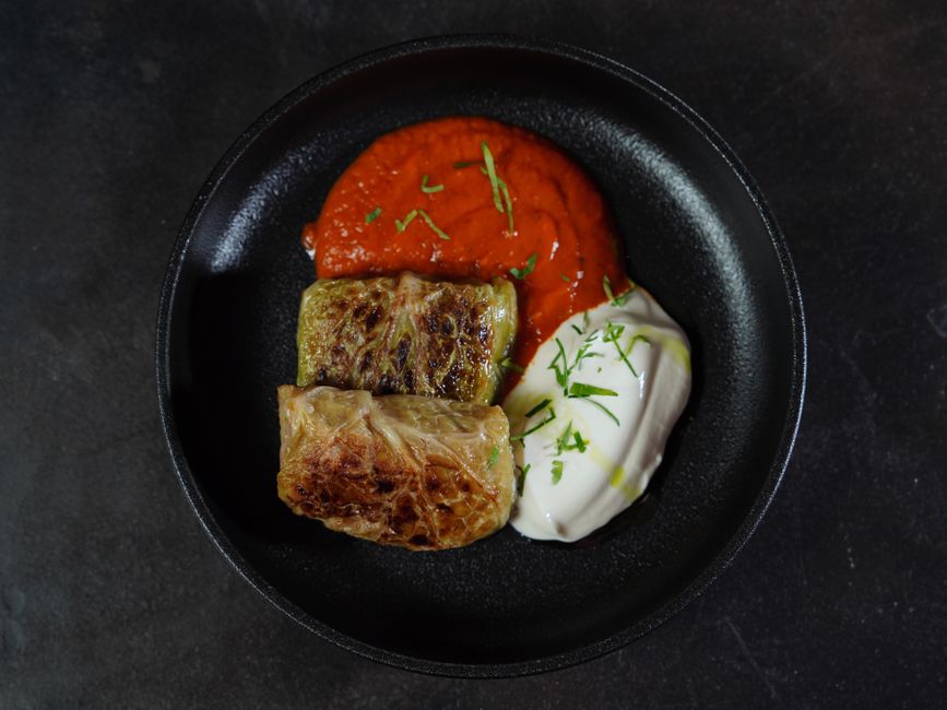 Photo by Nadin Sh on Pexels A scrumptious serving of cabbage rolls with tomato and yogurt sauces on a black plate. - Photo by Nadin Sh on Pexels