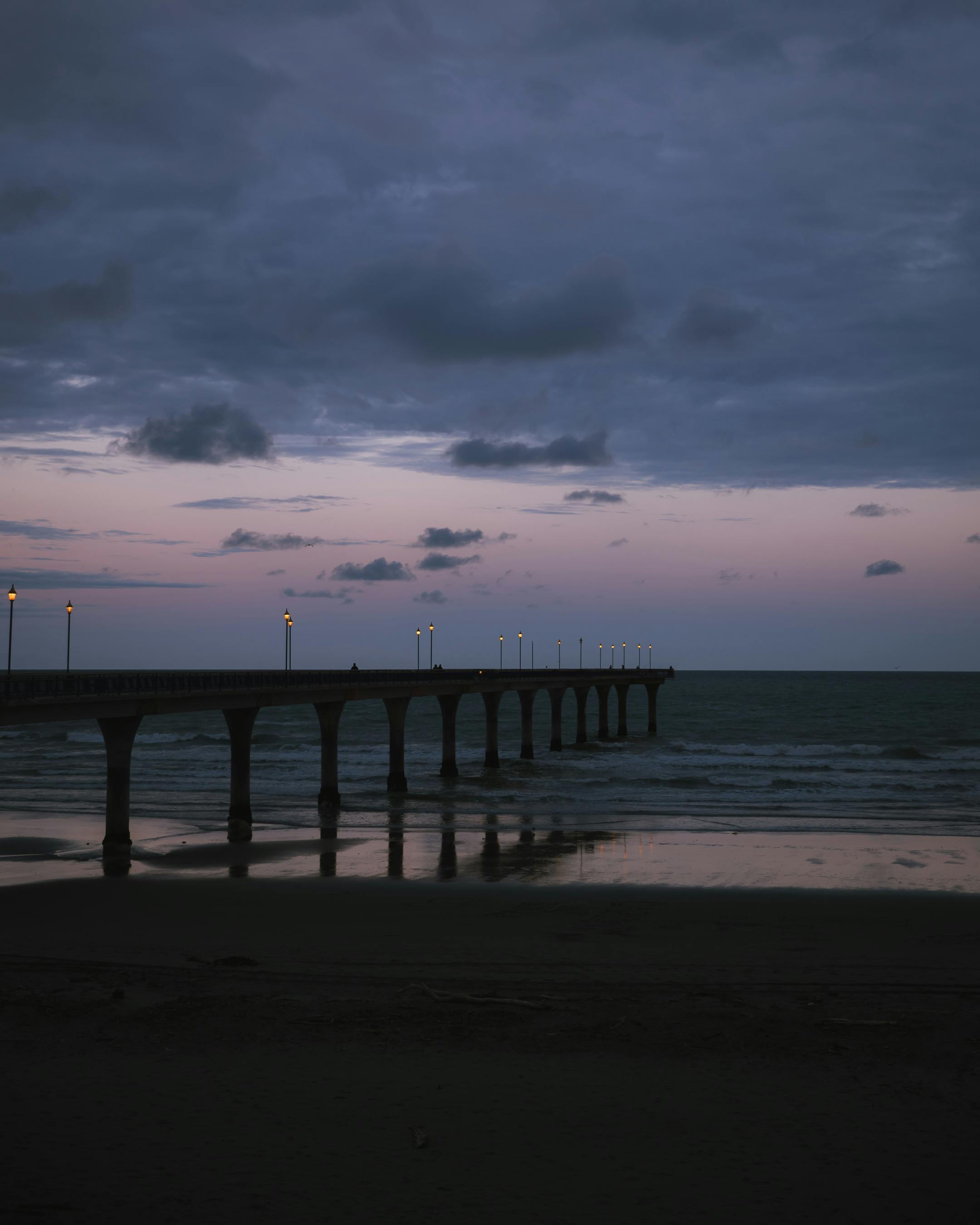 Peaceful scene of New Brighton Pier at dusk in Christchurch, New Zealand, reflection on calm sea.