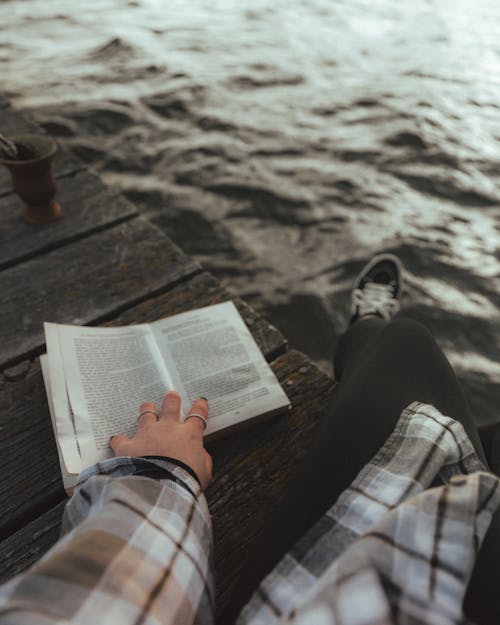 Woman Sitting with Book on Pier