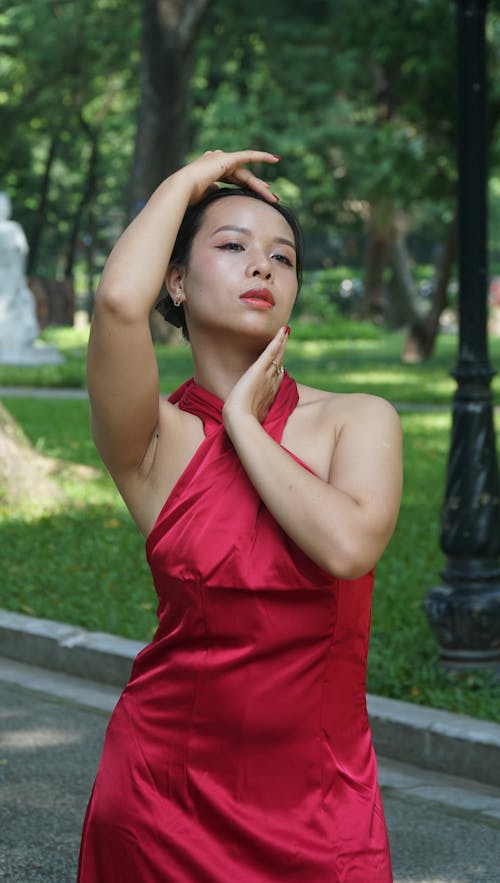 Young Woman in a Red Dress Standing in a Park 
