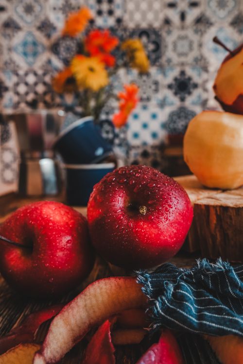 Free Vibrant red apples with water droplets on a rustic table in a cozy kitchen setting. Stock Photo