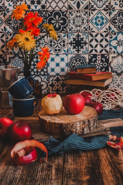 Free Warm, rustic kitchen scene with apples and vibrant flowers on wooden counter. Stock Photo